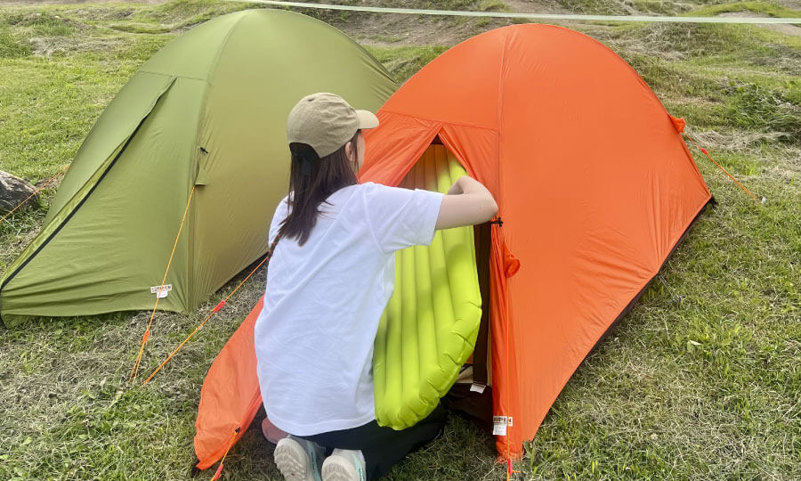 設営したテントにNIMOのスリーピングパッドを入れるスタッフ