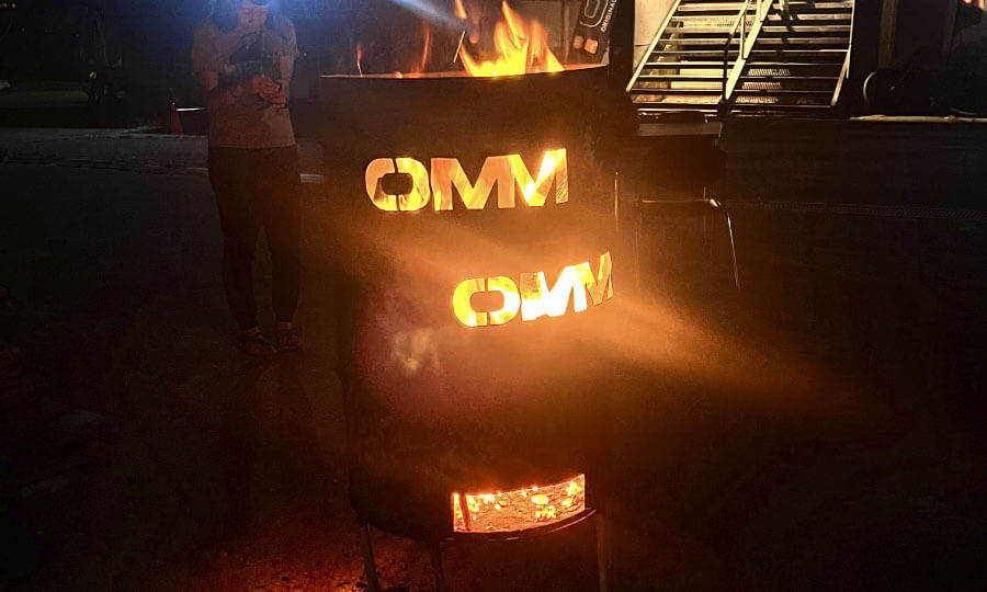 OMMの文字が型抜きされたドラム缶でキャンプファイヤー